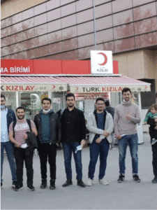 Yaseen Hemzawi stands smiling after donating blood with the Maser Team for Syrian youth, supporting the Red Crescent in Turkey.